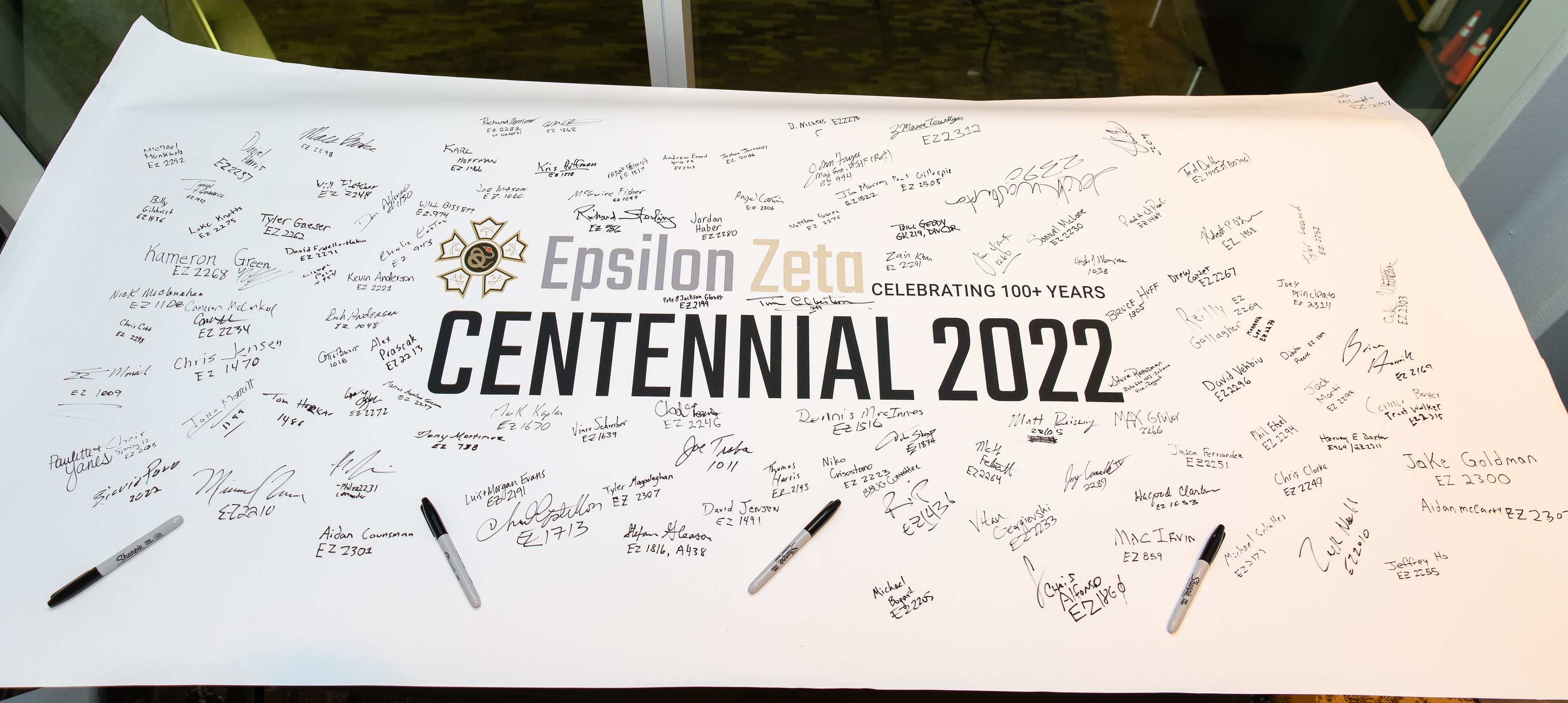 Sigma Nu brothers at centennial celebration event with banner display